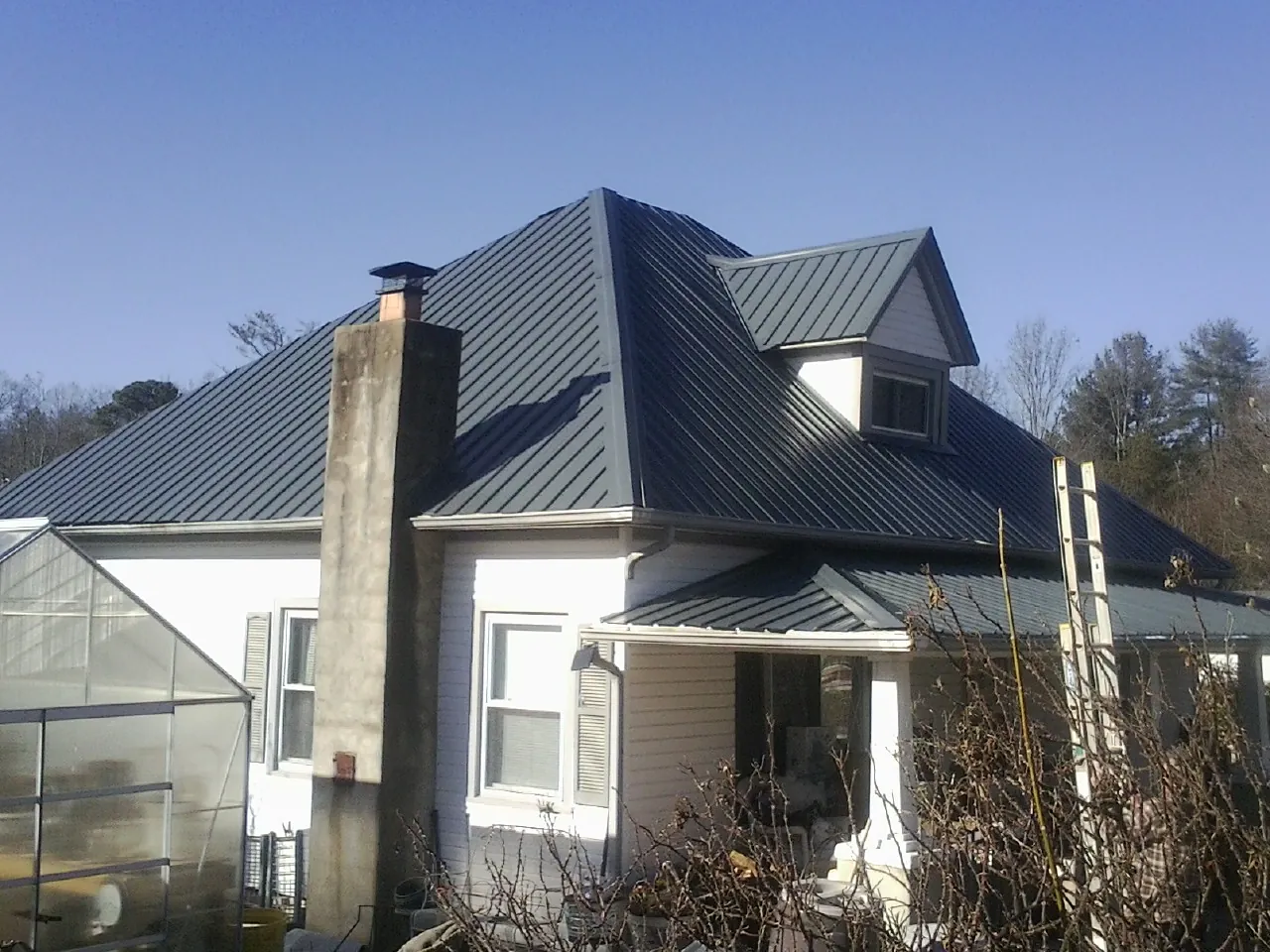 Dark blue standing seam metal roof on a white farmhouse with dormer — Slate & Tile Roof Repair by Roofing Brothers in Avinger