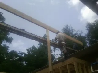 Carpenter setting a ridge beam over a new addition frame — Ice Dam Removal by Roofing Brothers in Avinger