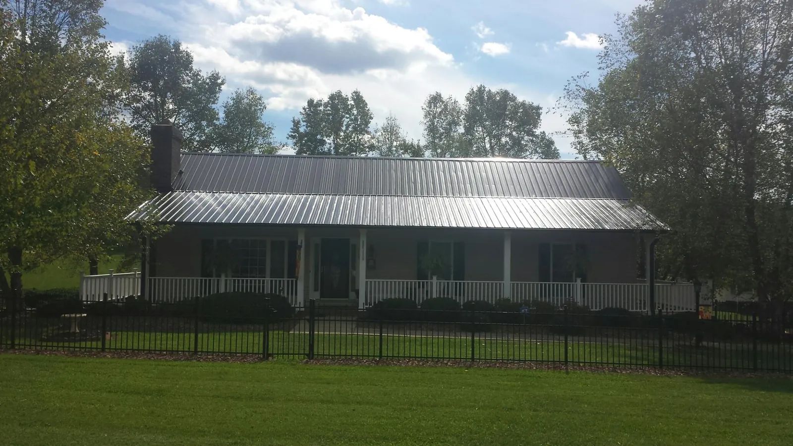 Gray metal roof on a brick ranch with a full width front porch — Gutter Guard Installation work by our crew in Avinger