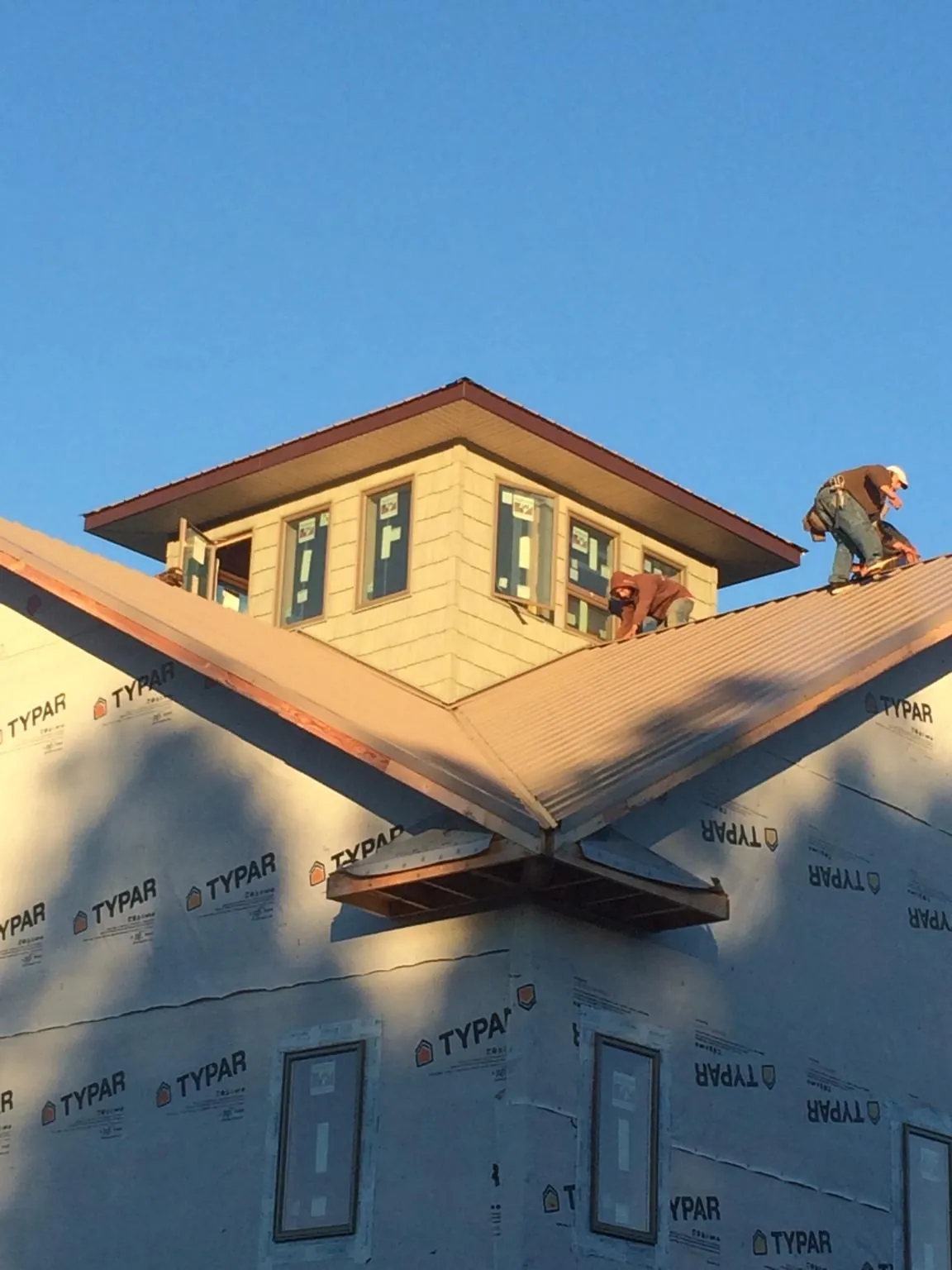 Roofers working around a rooftop cupola on a new metal roof at sunset — Roof Waterproofing in Avinger by Roofing Brothers